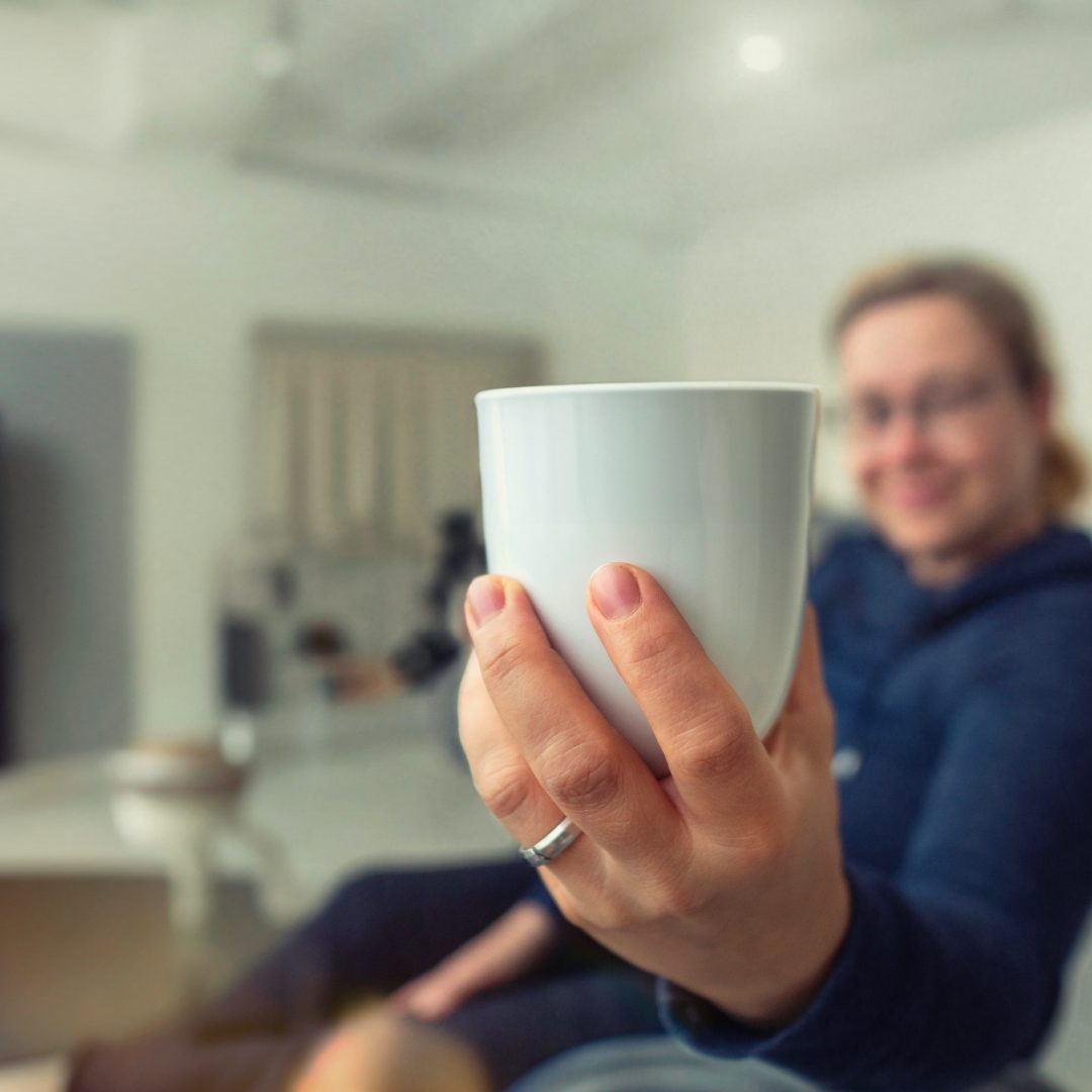 Katrin hält einladend eine Tasse hin Katrin hält einladend eine Tasse hin